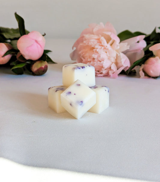 close up of peony scented wax melts with pink peonies in the background