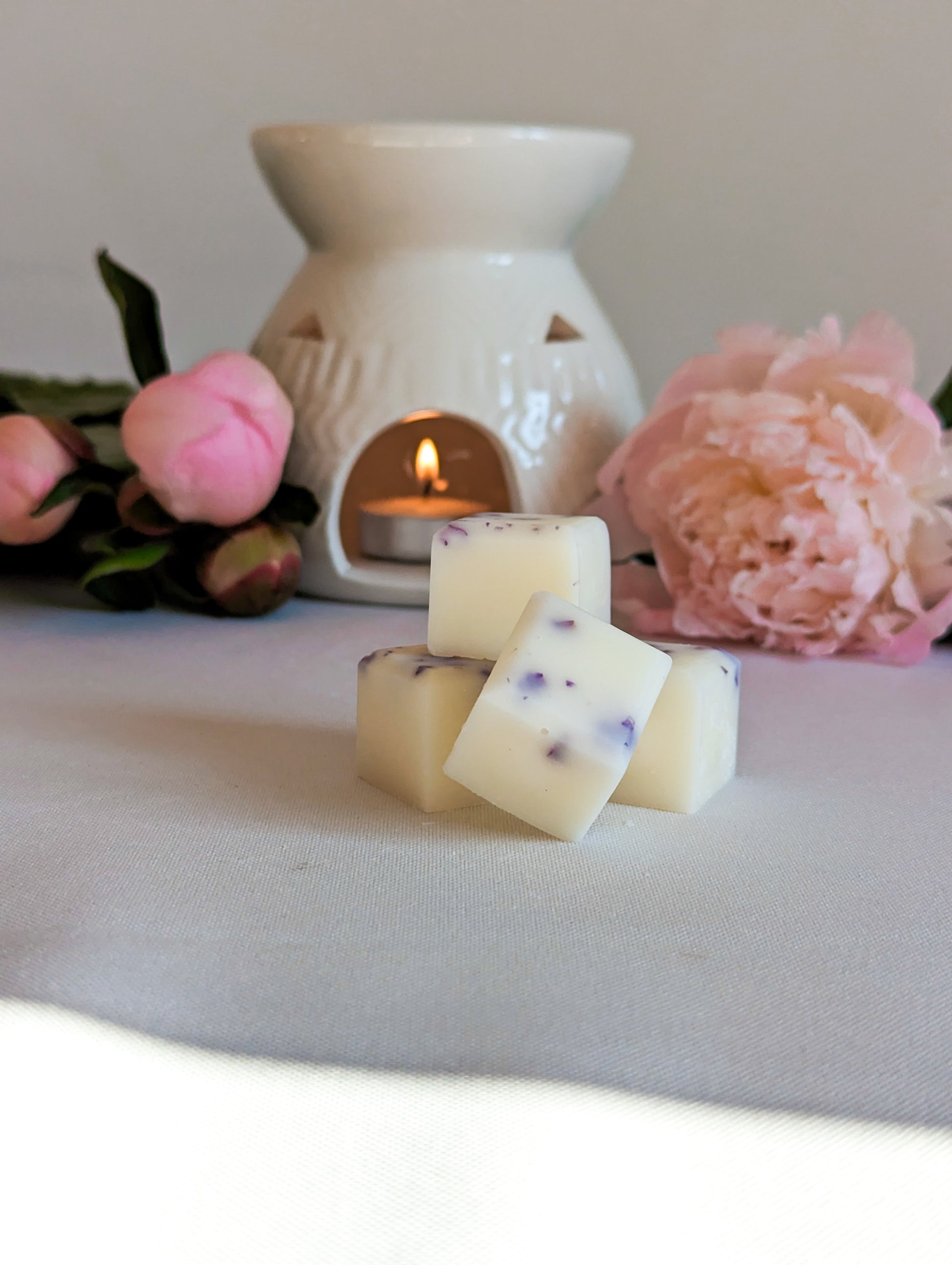 wax melts that are peony scented with a wax melt burner and pink peonies in the background